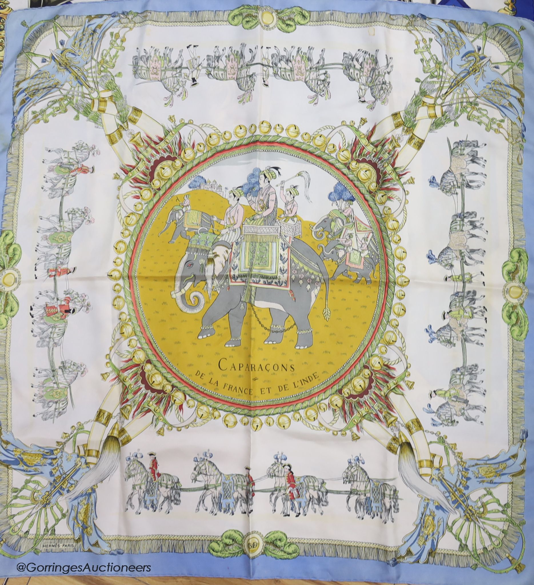 Three vintage Hermes silk scarves, 'Caparacons' (white ground), 'La Camargue' (red ground), and 'Ludovicus Magnus' (blue ground)